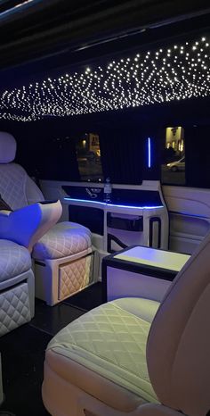 the interior of a luxury car with white leather seats and blue lights hanging from the ceiling