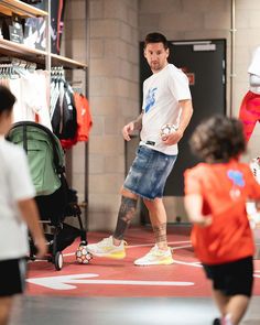 a man in white shirt and blue shorts playing with a ball while other people watch