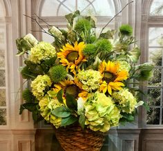 a basket filled with lots of green and yellow flowers