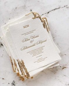 the wedding stationery is laid out on top of each other, with gold foil