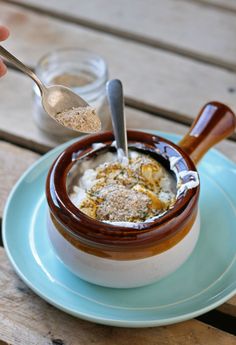 a bowl of food on a plate with a spoon in it and some salt next to it