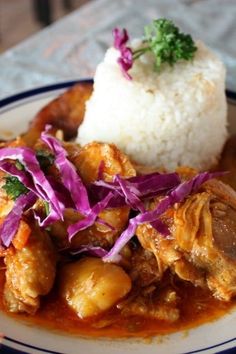 a white plate topped with meat and veggies covered in gravy next to rice