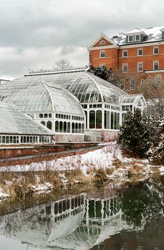 a building with many windows next to a body of water in front of snow covered ground