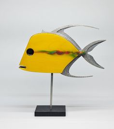 a yellow fish sculpture sitting on top of a metal stand