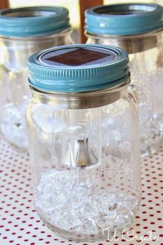 four mason jars filled with ice sitting on top of a red and white tablecloth