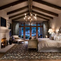 a large bedroom with a fireplace and chandelier