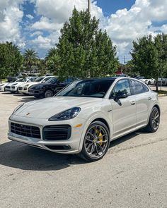 a white porsche cayen is parked in a parking lot with other cars behind it