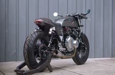 a black motorcycle parked on top of a cement floor next to a metal garage door