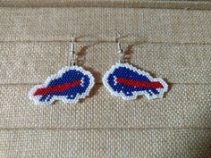 pair of beaded buffalo logo earrings sitting on top of a piece of fabric,