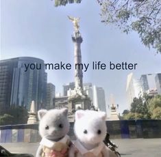 two white teddy bears sitting next to each other in front of a statue with the words you make my life better