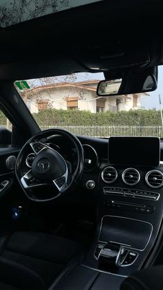 the interior of a car with black leather seats and steering wheel, in front of a house