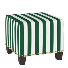 a green and white striped ottoman sitting on top of a wooden leg stool with studded trim