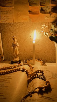 an open book sitting on top of a table next to a candle