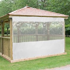 a gazebo in the middle of a grassy area with trees and bushes behind it