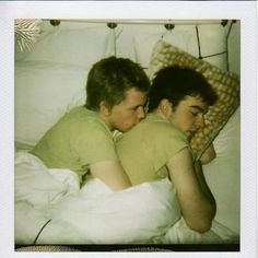 two young men laying in bed next to each other