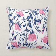 a white pillow with pink and blue flowers on it's front, against a wall