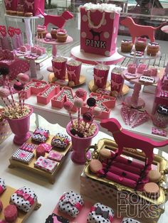 a table topped with lots of pink cupcakes and desserts covered in fondant