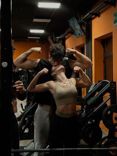 a man standing next to a woman in front of a gym machine with his arm up