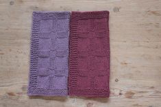 two knitted scarves sitting on top of a wooden table