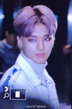 a man with purple hair is looking at the camera