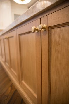 a kitchen with wooden cabinets and brass knobs on the door handles, along with hardwood flooring