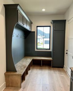 an empty mud room with built in benches and cabinets on either side of the window