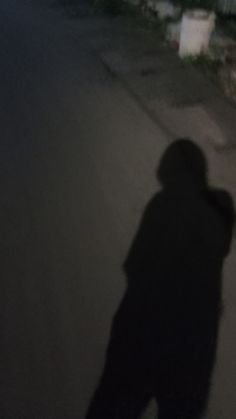 the shadow of a person holding a skateboard in front of a house at night