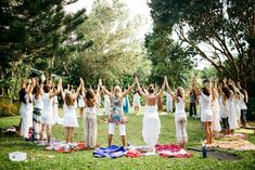 a group of women standing on top of a lush green field holding their hands in the air