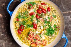 a pot filled with corn and tomatoes on top of a wooden table