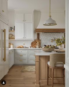 a kitchen with white cabinets and wood floors, an island countertop and two stools