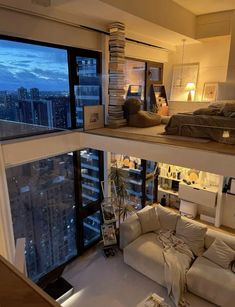 a living room filled with furniture and a large window overlooking the city at night time