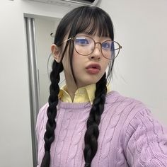 a girl with glasses and braids in front of a mirror