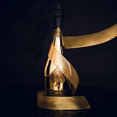 a bottle of champagne with a ribbon around it on a black surface, against a dark background