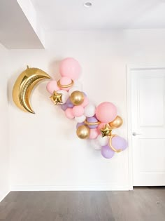 balloon garlands and balloons are arranged on the wall in an empty room with a door