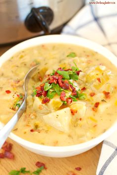 a white bowl filled with potato soup on top of a wooden table next to a crock pot