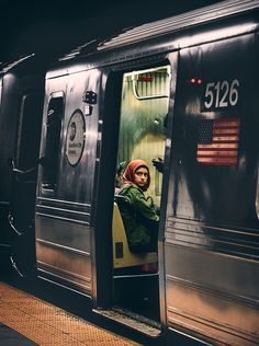 a man sitting in the doorway of a train at night with an american flag on it