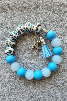 a bracelet with blue beads and a leopard print keychain on top of carpet