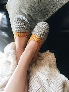 a woman's feet with crocheted slippers resting on a couch