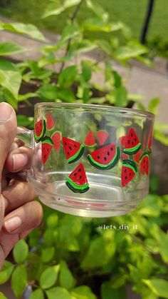 a person holding up a glass cup with watermelon designs on the inside and outside