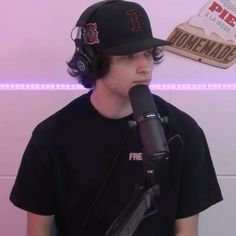 a young man wearing headphones and a baseball cap sits in front of a microphone