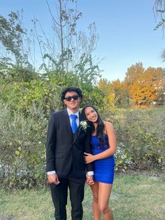 a man in a suit and tie standing next to a woman wearing a blue dress