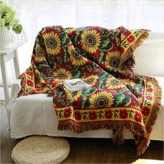 a couch covered in a colorful blanket next to a white table with flowers on it