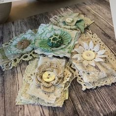 several pieces of lace with buttons and flowers on them sitting on top of a wooden table