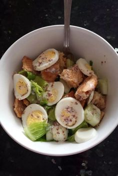 a white bowl filled with salad topped with hard boiled eggs