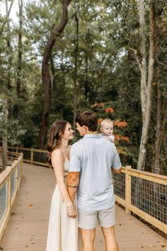 a man and woman holding a baby while standing on a bridge