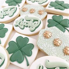 shamrock cookies decorated with royal icing and gold leaf decorations are arranged on a table