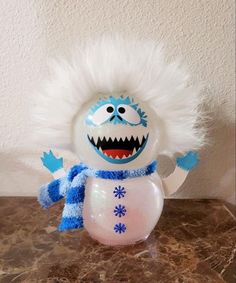 a frosty snowman with white fur on it's head and blue eyes