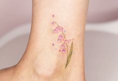 a small flower tattoo on the side of a woman's foot with pink flowers