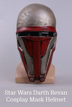 a red and silver helmet on top of a wooden head mannequin's head