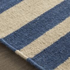 a blue and beige striped rug on top of a wooden floor